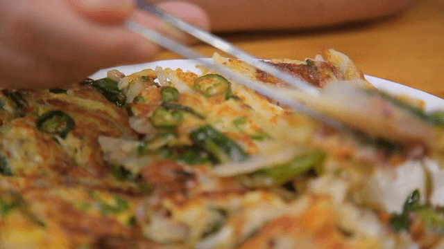 Seafood and green onion pancake being picked up with chopsticks