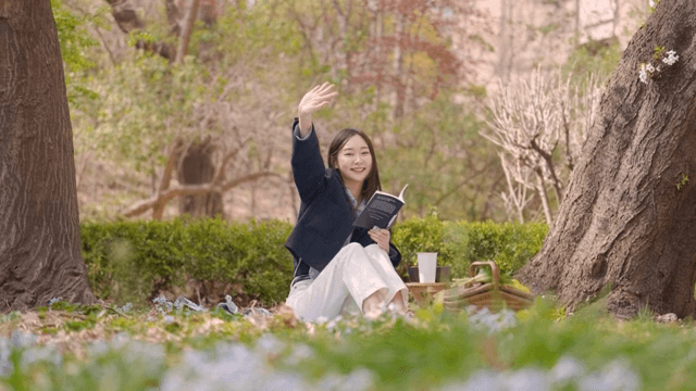 Woman joyfully recognizing someone while reading in a park