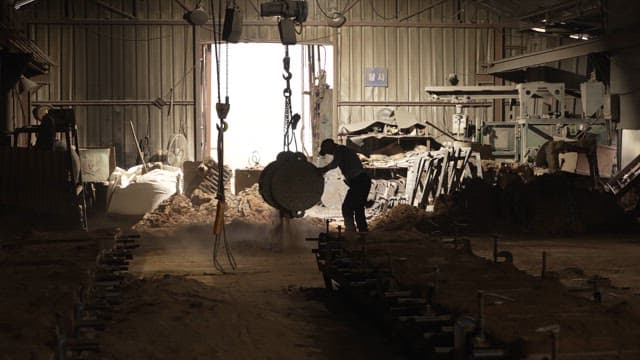 Worker handling metal parts in a factory