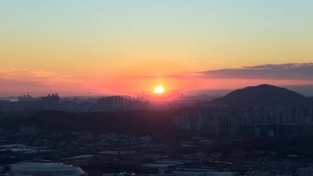 Sunset over a city skyline with mountains