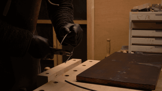 작업장에서 금속 와이어를 도구로 휘는 장인