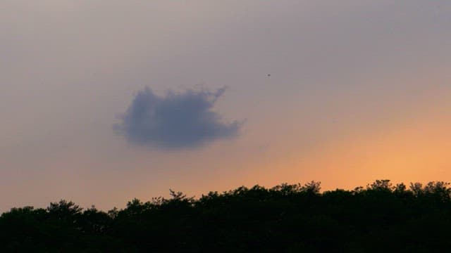 Sunset red sky above a forested hill with clouds