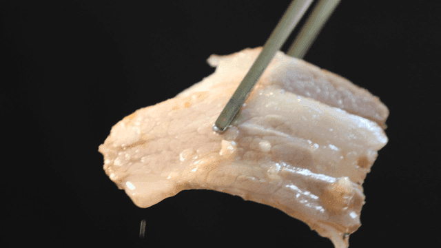 Juicy boiled pork jowl held with chopsticks