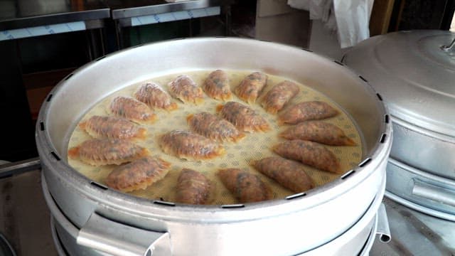 Kimchi dumplings steaming in a steamer in the kitchen