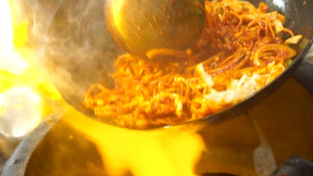 Cooking spicy stir-fried jjamppong with vegetables in a wok