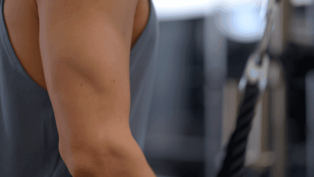 로프를 사용하여 헬스장에서 팔 운동하는 남성