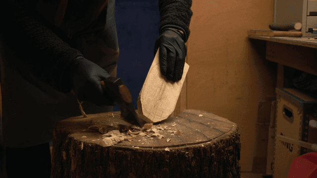 작업실에서 도끼로 나무를 조각하는 공예가