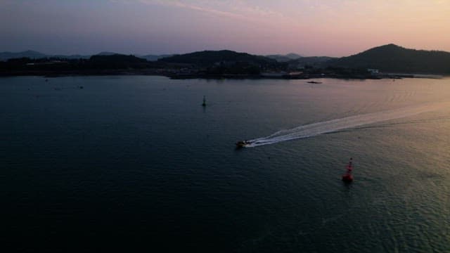 평화로운 해질녘의 바다를 가로지르는 보트