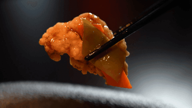 Chopsticks picking tangsuyuk soaked in vegetables and sauce