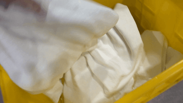 Yellow plastic box filled with white cloths