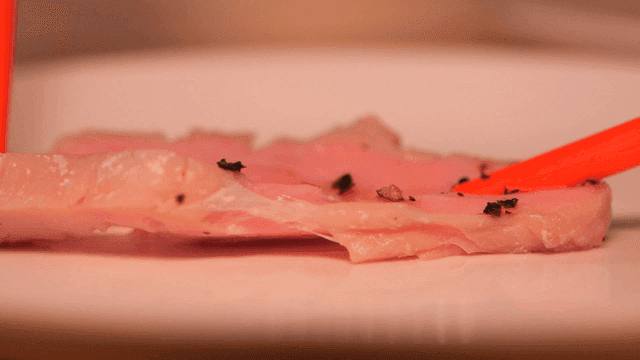 Chopsticks tearing piece of sous vide sirloin with pepper on plate