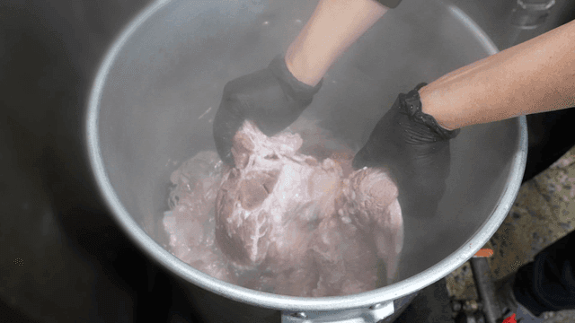 Boiling meat in a large pot with steam