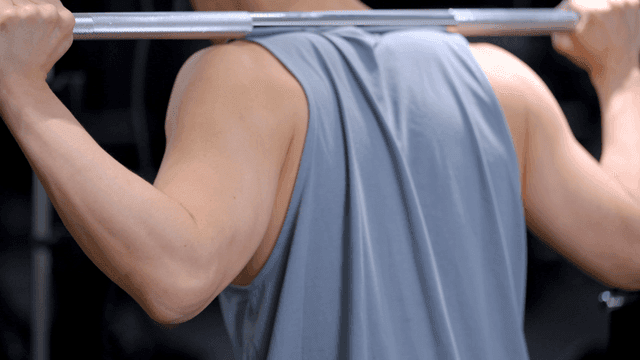 헬스장에서 어깨에 무게를 지고 스쿼트를 하는 남자