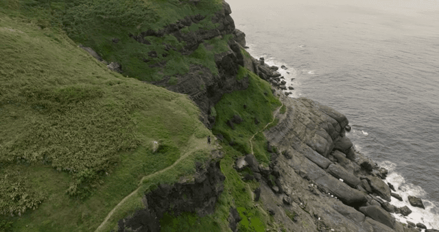 Person running along a coastal cliff