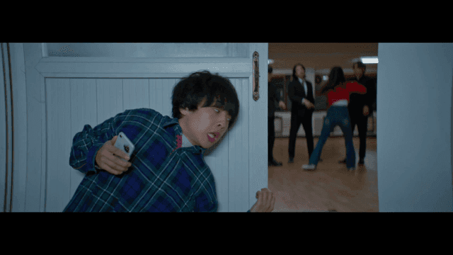 싸우고 있는 사람들과 문 넘어 휴대폰으로 신고하는 남자