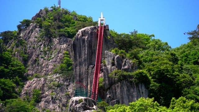 Person climbing the red steps in a mountain covered with lush green trees