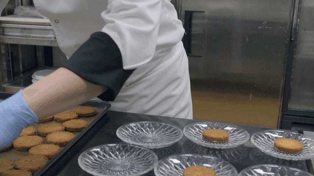 Chef arranging cookies on plates in kitchen