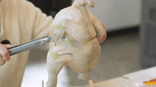 Boiled chicken being prepared with tongs