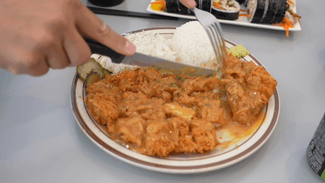 밥과 샐러드가 곁들여진 돈가스를 자르는 모습