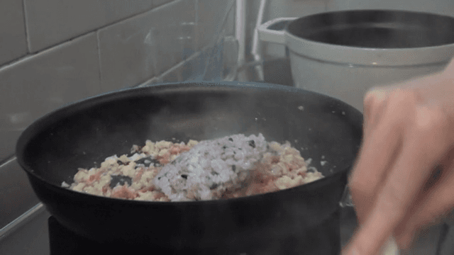Rice added to the stir-fried ingredients in a frying pan