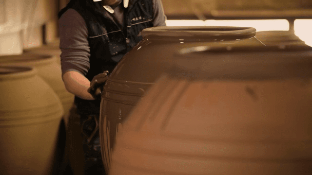 Person applying glaze to large pottery