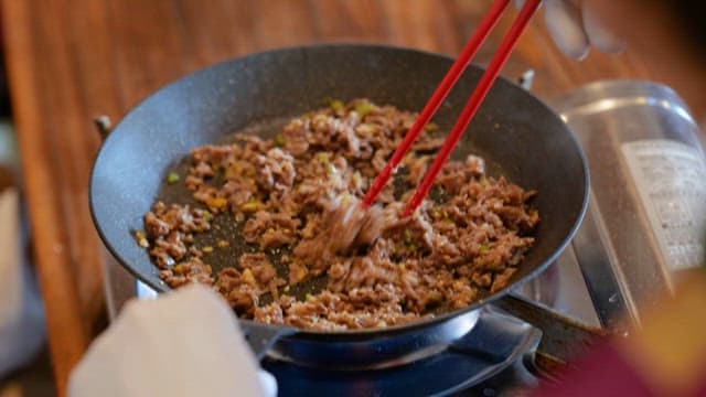 Cooking Stir-fried Beef with Red Chopsticks on Gas Burner