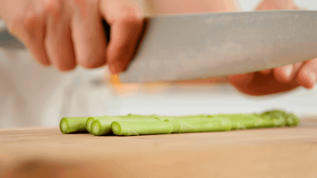 Hands cutting asparagus on cutting board