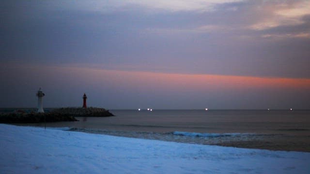 Winter sunset over a tranquil beach with two lighthouses