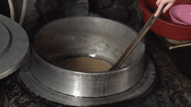 Wooden spatula stirring ground acorn liquid in a pot