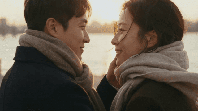 Couple kissing by river at sunset