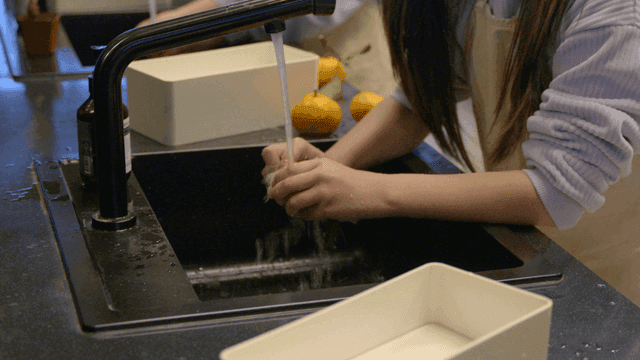 Woman washing tangerines under running water