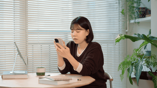 Frustrated woman looking at her smartphone at table