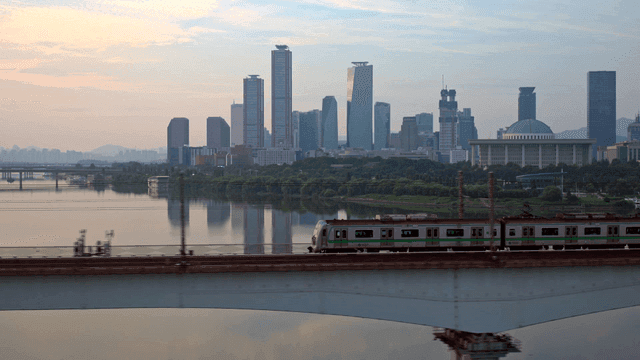 Train crossing a bridge with city skyline
