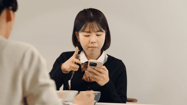 Female student using her cell phone during meal