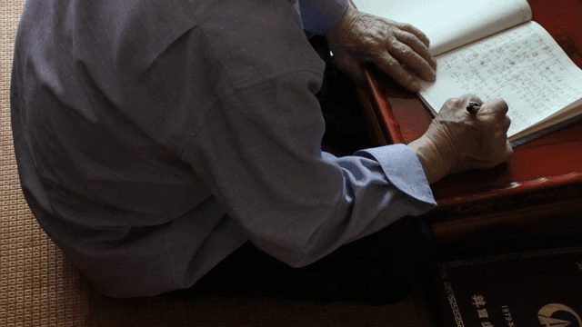 노트에 글을 쓰는 노인