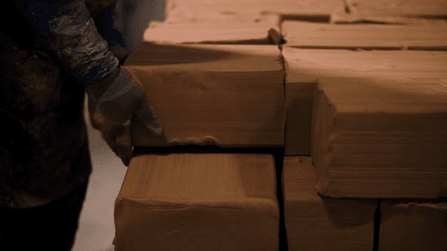 작업장에서 점토 블록을 쌓는 작업자