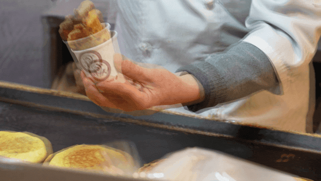 노점상이 그릴에서 호떡을 종이컵에 담는 모습