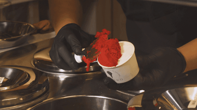 Hands putting red sorbet into cup