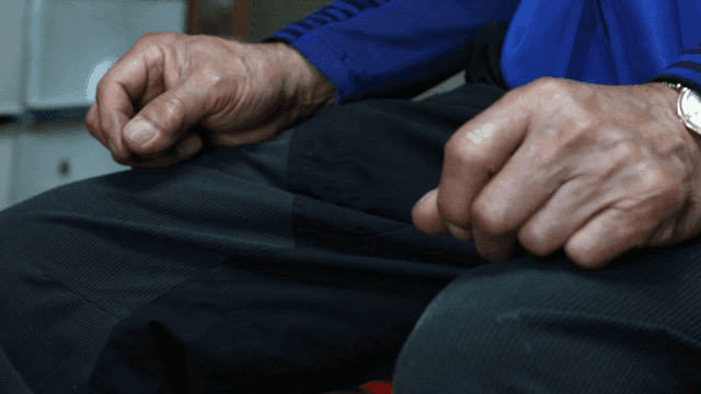 Elderly hands resting on knees indoors