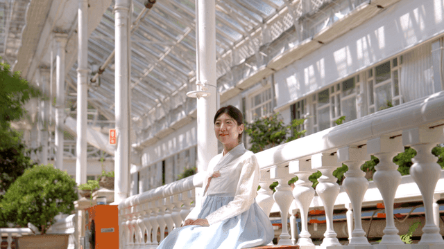 온실에서 한복을 입고 앉아 있는 여성