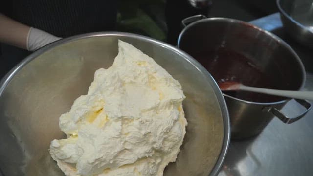 Mixing fresh cream with homemade berry jam in a kitchen