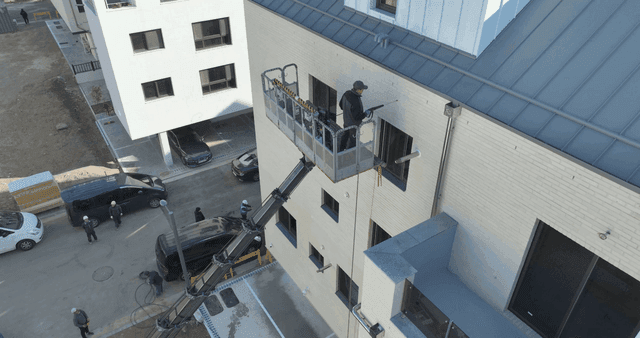 Worker painting exterior of building