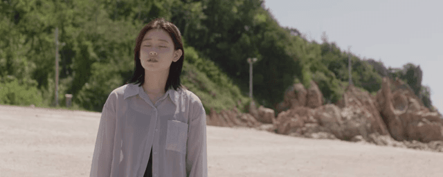 햇살이 비치는 해변에 서 있는 여성