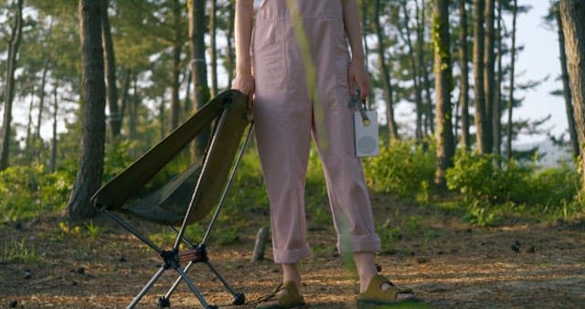 Person Walking with a Camping Chair in Forest