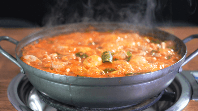 Spicy chicken offal soup in boiling pot on table burner