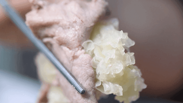 Chopsticks holding oyster mushrooms and beef