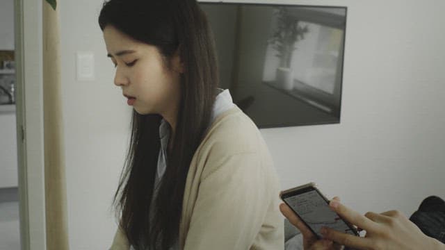 밝은 방에 앉아 침울한 표정을 짓는 여자