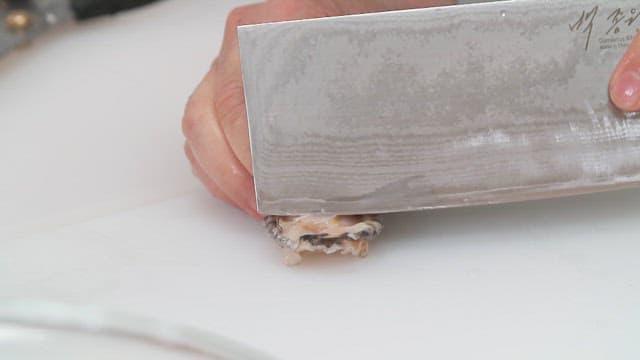 Cutting a abalone with a knife on a white cutting board