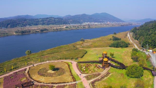 View of a serene park with pathways and scenic river surrounded by nature