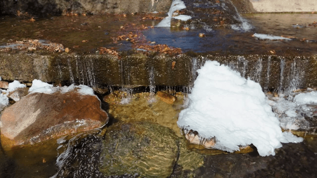 눈 덮인 바위 위로 흐르는 물